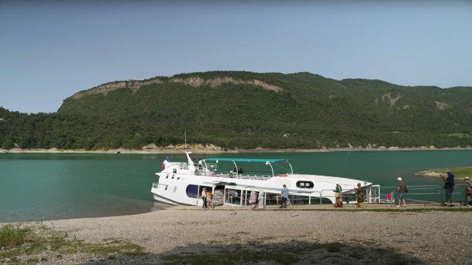 Des personnes s'apprêtent à embarquer sur un petit bateau mouche sur un lac