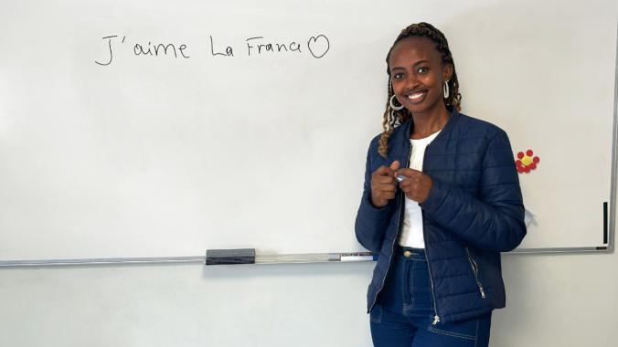 Une jeune femme se tient devant un tableau blanc en cours de français débutant