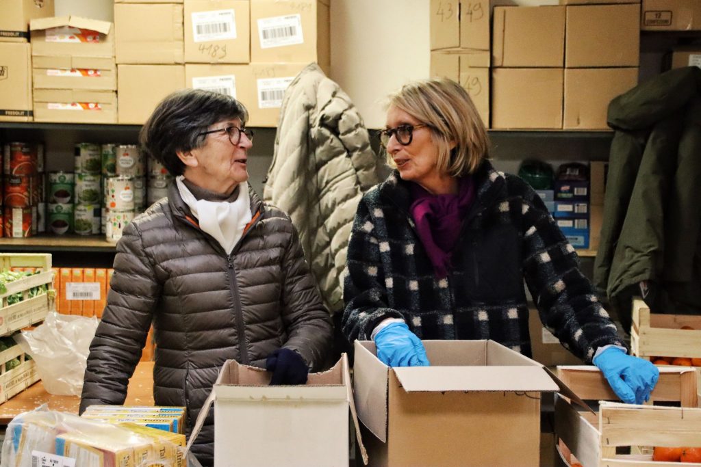 Deux bénévoles souriantes en train de discuter et trier des caisses de denrées alimentaires