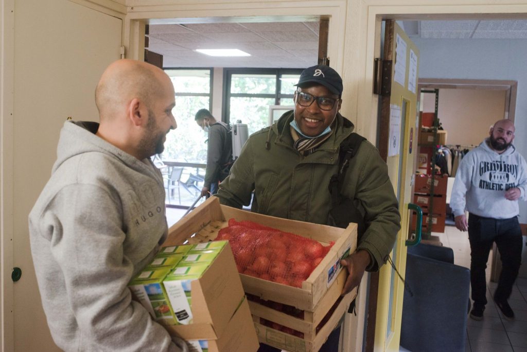 Deux bénévoles souriants en train de porter des caisses de denrées alimentaires